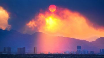 El sol sale entre el denso humo que cubre el cielo de la famosa calle de los casinos en Las Vegas, debido a un gran incendio que está devorando un área cercana a la ciudad.