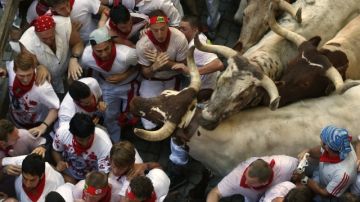 Varios mozos se agolpan en un momento del recorrido de los toros en el  encierro de los sanfermines de Pamplona.