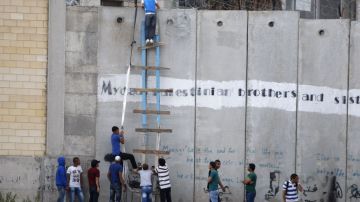 Palestinos escalan el muro par asistir a los rezos.