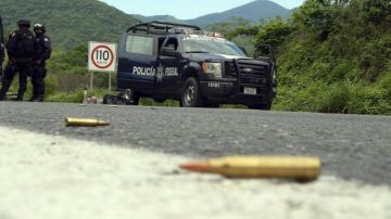 Agentes federales y soldados del Ejército mexicano resguardan una carretera en el municipio de Arteaga, en el estado mexicano de Michoacán, donde se registró uno de los varios ataques contra oficiales federales ocurridos en este estado.