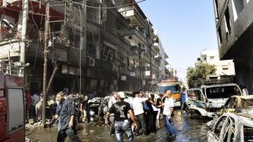 Varias personas inspeccionan las daños producidos tras una explosión  ayer en el barrio de Jaramana, en Damasco, que dejó muertos y heridos.