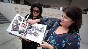Yamileth Escobar (der.) y  María de los Ángeles Domínguez muestran fotos de su boda frente al edificio de Inmigración.