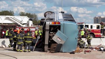 Bomberos trabajan para auxiliar a los pasajeros del autobús que se accidentó en Indianápolis, Indiana, ayer.