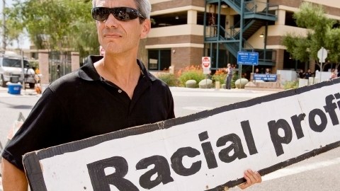 Un activista sostiene un cartel en referencia al perfil racial.