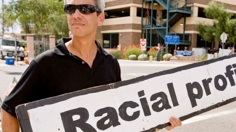 Un activista sostiene un cartel en referencia al perfil racial.