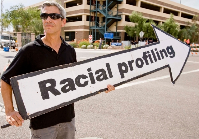 Un activista sostiene un cartel en referencia al perfil racial.