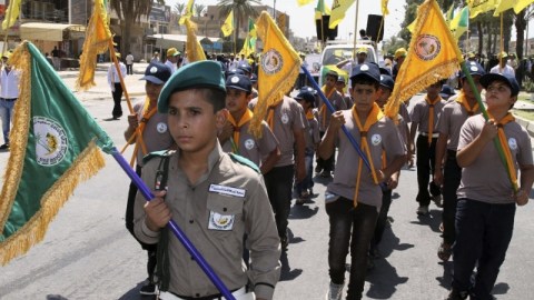 Un grupo de jóvenes 'scouts', simpatizantes de Hezbolá, sostiene banderas y corea consignas en manifestación en Bagdad (Irak).