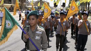Un grupo de jóvenes 'scouts', simpatizantes de Hezbolá, sostiene banderas y corea consignas en manifestación en Bagdad (Irak).