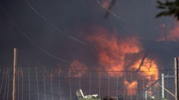 Dave Clark, de Twin Pines, dice a un vecino que su casa está bien, mientras su propia casa arde detrás de él.