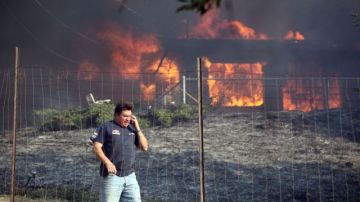 Dave Clark, de Twin Pines, dice a un vecino que su casa está bien, mientras su propia casa arde detrás de él.