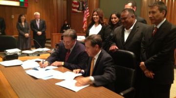 David Cavazos, nuevo administrador de la ciudad de Santa Ana, firma su contrato acompañado del alcalde Miguel Pulido.