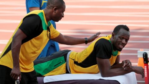 Usain Bolt (der.) recibe una palmada en la espalda de uno de sus compañeros durante la práctica de ayer.
