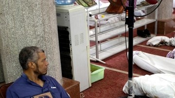 Un hombre sostiene una copia del Corán sentado junto a docenas de cadáveres en la mezquita al-Imene en El Cairo, Egipto.