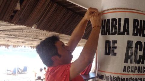 Un comerciante coloca un letrero en un negocio cerca de la playa, en Acapulco