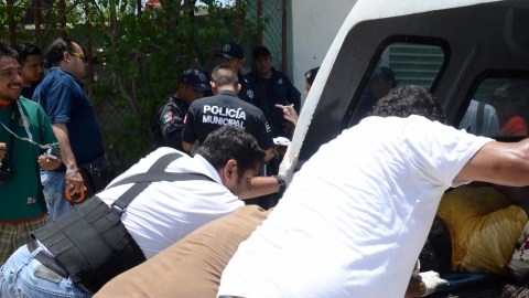 Empleados de la Oficina del Forense recogen los cuerpos de individuos acribillados.