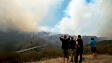 Varias personas miran hacia el Cañón del Río Tuolumne mientras el incendio se mueve hacia el este por la carretera 120 en Stanislaus National Forest, California.