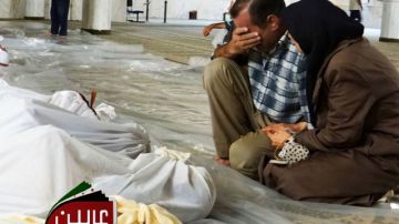 En esta foto de TV aparecen un hombre y una mujer llorando sobre los cadáveres de varios sirios después de un presunto ataque con gas venenoso disparado por las fuerzas del régimen, según denuncias de  los activistas en Arbeen, Damasco.