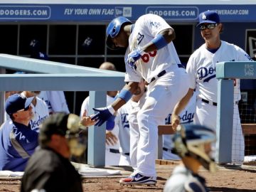Yasiel Puig (66) es felicitado por el coach Mark McGwire por su jonrón, mientras lo observa el mánager Don Mattingly en el duhout.