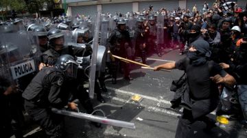 Manifestantes enmascarados chocaban con la policía antidisturbios durante marcha en el Distrito Federal que se dirigía hacia  la Cámara de Diputados, ayer.