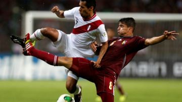 Carlos Lobaton (izq.) disputa el esférico ante el venezolano Tomás Rincón, en duelo eliminatorio rumbo a la Copa del Mundo.