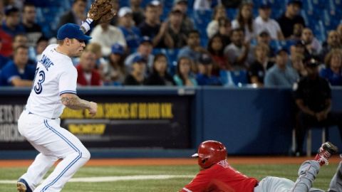 Erick Aybar se barre de cabeza para llegar quieto a la tercera base ante la mirada der Brett Lawrie.