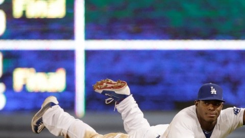 Yasiel Puig levanta su guante para mostrar que atrapó un batazo del jugador de Arizona,  Chris Owings.