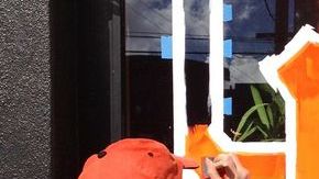 Una chica pinta las ventanas de un negocio con las iniciales de los Gigantes de San Francisco.