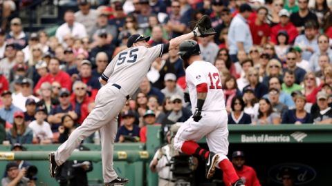 Lyle Overbay (55) no alcanza a atrapar la pelota lanzada por el antesalista yankee, Mark Reynolds y Mike Napoli (12), de los Medias Rojas, se enbasa en primera.