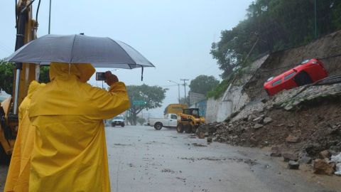 Un auto cae en medio de un derrumbe en un sector de Acapulco, producido por las fuertes lluvias que están castigando parte del territorio mexicano.