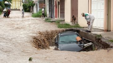 Un hombre observa su vehículo en un hueco y atrapado por las corrientes, ayer, en la ciudad de Chailpancingo (México).