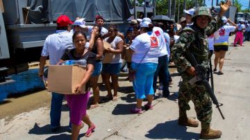 Damnificados por las lluvias cargan con víveres en el "Boulevard de Las Naciones", en Acapulco.