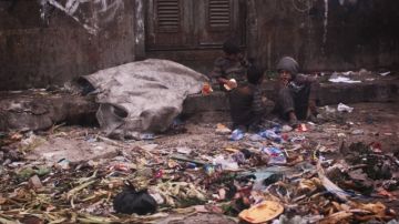 Dos niños sirios mendigos se sientan entre la basura en la búsqueda de alimentos, ayer, en Alepo (Siria).