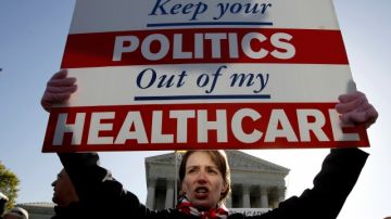 Una manifestante sostiene un cartel frente a la Corte Suprema en contra de la reforma de salud, un tema que sigue siendo polémico en Washington.