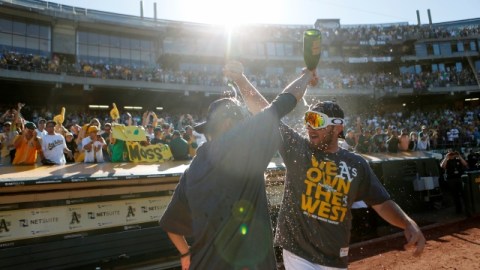 Ryan Cook (der.) y Jesse Chávez festejan con champaña el título divisional de la novena verde-amarilla.
