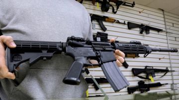 Un hombre muestra un rifle AR-15  de venta en una tienda de armas.
