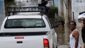 Un grupo de personas carga provisiones en una zona inundada, en una colonia del puerto de Acapulco (México), ayer.