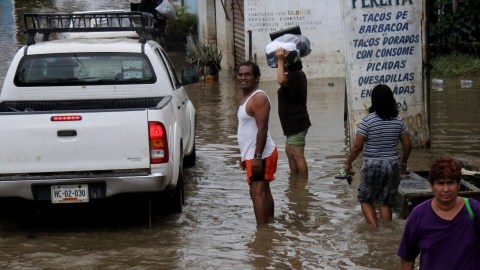 Un grupo de personas carga provisiones en una zona inundada, en una colonia del puerto de Acapulco (México), ayer.