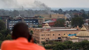 Un hombre hace una llamada telefónica mientras observa una columna de humo que se eleva sobre el centro comercial Westgate en Nairobi (Kenia).