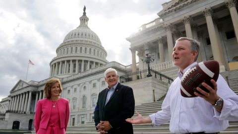 Los representantes republicanos Vicky Hartzle (izq.), Bob Gibbs y Tim Griffin (der.), hablan en las afueras del Congreso sosteniendo una pelota de fútbol americano, haciendo alusión a que el balón ahora está en la cancha del Senado, en referencia a la discusión de un proyecto de presupuesto.