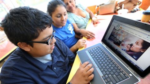 Una madre y sus hijos revisan la página de inscripción en línea de Covered California.
