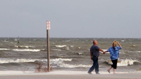 Residentes caminan frente a un mar embravecido en Gulfport, Mississippi.