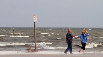 Residentes caminan frente a un mar embravecido en Gulfport, Mississippi.