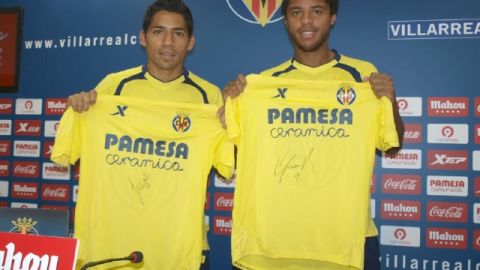 Javier Aquino (izq.) y Giovani dos Santos muestran las camisetas firmadas que donaron a damnificados de tormentas en Mexico.
