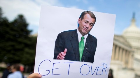 Un manifestante sostiene un cartelón contra el líder de la Cámara Baja John Boehner, instándolo a pasar el presupuesto.