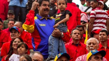 El presidente de Venezuela, Nicolás Maduro (cen.), sostiene a Jorge Alejandro, nieto del fallecido Hugo Chávez, en el festejo.