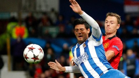 El delantero mexicano Carlos Vela, de la Real Sociedad, disputa el esférico con Jonny Evans, del Manchester United