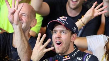 El alemán de Red Bull, Sebastian Vettel, y parte de su equipo, muestran con sus manos el número de títulos de Fórmula Uno que ha ganado.