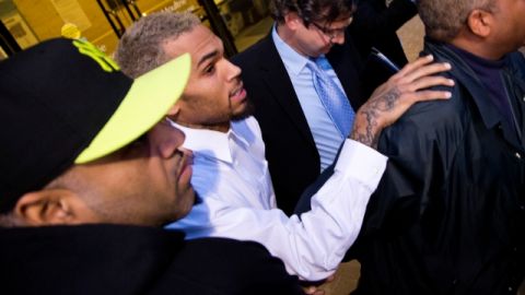 Guardaespaldas rodean a Chris Brown al salir el cantante ayer del tribunal en Washington. Un cargo de agresión contra el cantante fue reducido de delito grave a delito menor.