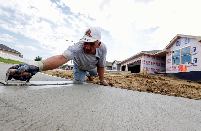 Un trabajador le da forma a una acera frente a un grupo de nuevas casas construidas en Omaha, Nebraska. Según un estudio del BPC, la reforma migratoria impulsaría el sector de la construcción.