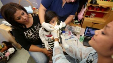 Mireya Rodríguez (der.), higienista dental del proyecto de dentista virtuales, limpia los dientes de Valentina Murillo, de 2 años.